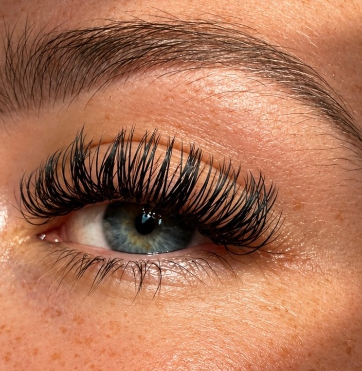 One by One wimperextensions bij een blauw oog in warm zonlicht